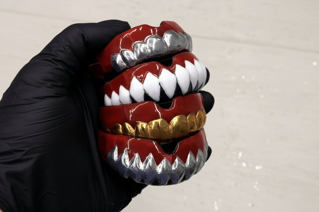 Stack of colorful grills with red, gold, and silver accents on a neutral background